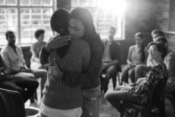 Women hugging in group therapy session