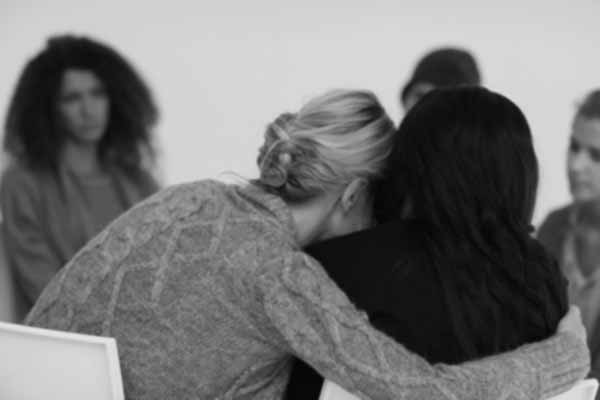 Women embracing in rehab group at therapy